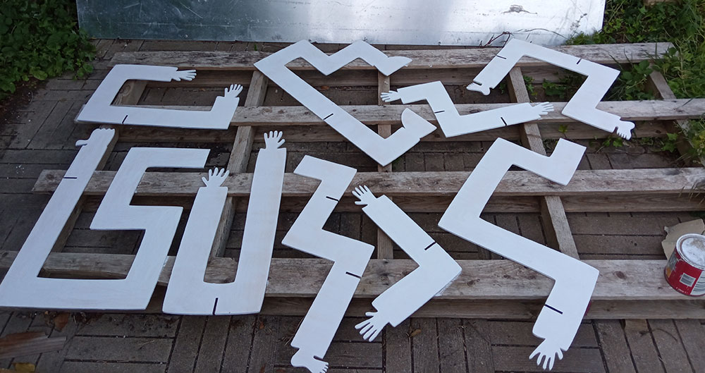 The nine large limb-shapes to be used are primed and laid out over a wooden support with a can of primer/white paint lying next to them.