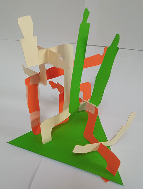 orange and green cardboard stuck together to make a 3D shape on a triangular base.